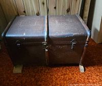 Front view of closed brown steamer trunk with metal hardware
