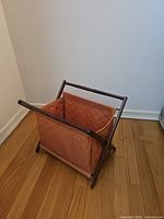 Perspective view of folded wood magazine rack with orange quilted liner