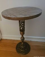 Entire side table showing round wood top and ornate brass-tone metal pedestal and base
