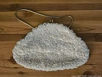 Front view of white beaded handbag showing beadwork and snake chain strap