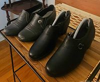 Grey and black pairs of women’s size 9 low heel dress shoes on table, black pair fitted with spring shoe trees