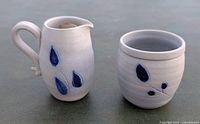 Pitcher and cup shown from front angle highlighting cobalt blue leaf and berry designs.
