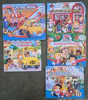 Front view of the five Fisher Price Little People board books arranged in two rows on carpeted floor.