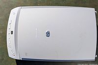 Top view of HP ScanJet 4470c flatbed scanner showing control buttons and HP logo on cover. The scanner is light gray with some minor wear marks.