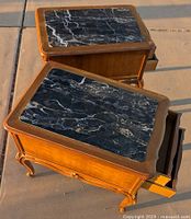 Pair of marble topped wooden nightstands/end tables viewed at angle, showing decorative legs and marble tops.