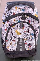 Front view of the rolling backpack showing the comic strip style Disney character print and zippered compartments.