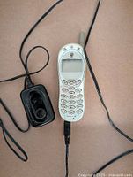 Motorola 120E cellphone connected to charger on brown background