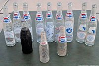 Front view presenting entire lot of 9 Pepsi bottles including Bicentennial editions and vintage smaller bottles.