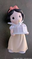 Front view of Snow White Precious Moments figurine holding a birthday cake with one candle lit