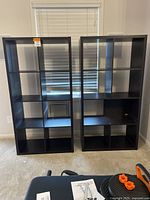 Two dark brown IKEA Kallax bookshelves side by side in room, showing full front view and size.