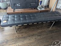 Full view of the black leather bench with metal legs placed in a living room area.