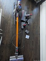 Overview of vacuum, wand, floor head, attachments and charger laid on floor