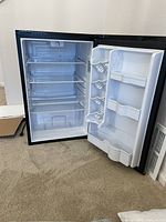 Open view of the Danby mini fridge showcasing three wire shelves, clear crisper drawer at the bottom, and door storage compartments for small items and bottles. Temperature control dial visible at top interior.