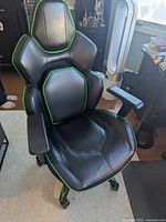 Green and black fully adjustable gaming chair with padded ergonomic design and black faux leather with green edges