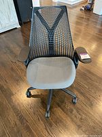 Front view showing grey seat cushion, black mesh back, adjustable armrests, and five-star caster base