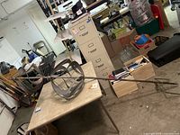 Full view of metal wind spinner sculpture on folding table with metal stake extending to floor