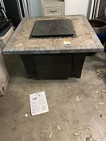 Front and top perspective showing square woven base and tile top with removable lid in place