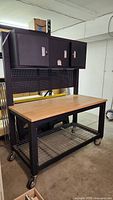 Full front view of rolling work bench with cabinets, pegboard, shelf and casters
