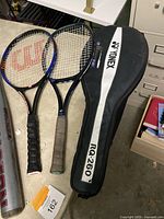 Two tennis rackets, one Wilson Matchpoint and one Yonex RQ-260 with Yonex racket case on a table.