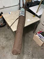 Long brown protective carrying bag for the umbrella with label attached showing Smith and Hawken branding.