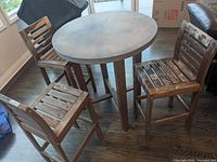 Three tall wooden chairs with slatted backs and seats, worn and weathered finish.