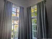 Four installed light blue Pottery Barn curtain panels on two windows.