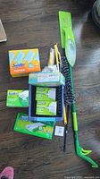 Lot contents showing Swiffer and Libman cleaning items: dusters, sweeping cloths, and mop with handle.