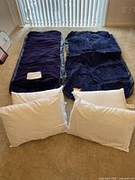 Two twin air mattresses laid flat on carpet with four white pillows in front.
