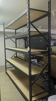 Side view of the tall black metal shelving unit, showing 5 shelves with wooden panels on each shelf.