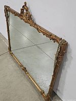 Side angle view showing gold ornate carved frame and hanging chains attached to the mirror edges.