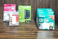 Full lot contents showing timer, lamp dimmer, portable hard drive, and CD-RW boxes in original packaging on a wooden surface.