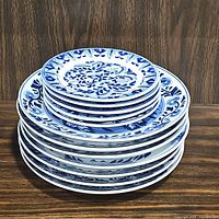 Stack of 6 dinner plates and 5 dessert plates showing blue and white floral and leaf patterns.