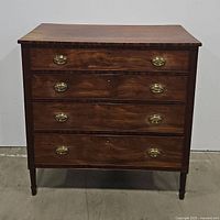 Front view of chest showing four drawers with brass hardware