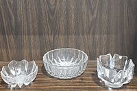 Three crystal bowls displayed on a dark wood surface showing size comparison and designs.