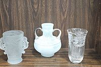 Three vases displayed on shelf: frosted vase with sea horse handles, two-handled frosted vase, and clear etched crystal vase.
