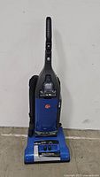 Front view of the Hoover WindTunnel upright vacuum cleaner in blue and black with attached handle and hose.