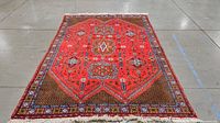 Full view of rectangular Moroccan vintage rug with red background and intricate geometric and floral patterns in multiple colors on floor.