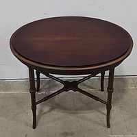 Full front-facing photo of the dark wood oval accent table showing the oval tabletop, four turned legs, and stretcher support.