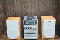 Full front view of Sony micro HiFi stereo system with two bookshelf speakers on each side, showing silver stereo unit and beige speaker grills with wood grain sides.