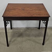 Front view of a rectangular vintage wooden tea table with four legs and decorative bracket supports at the corners.