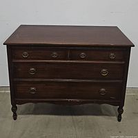 Front view of the wooden dresser showing four drawers; two small on top, two larger below, with metal ring pull handles.