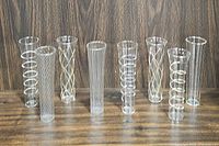 Eight glass bud vases lined up showing most designs and shapes