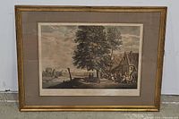 Full view of framed vintage art print showing village outdoor scene under large trees with people socializing.
