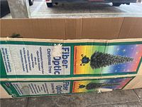 Box packaging for the 7 foot fiber optic Christmas tree showing branding, features, and color changing lighting.