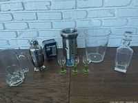 Photo of all bartender accessories laid out on wooden table against white brick wall background.