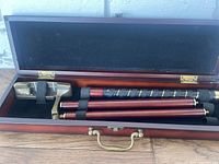 Golf putter set with wooden case, putter head, and three shafts arranged inside the case.