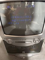 Front view of the Karaoke Vision DVD karaoke machine showing the CRT screen with distorted blue text and device controls below including CD/DVD player and speakers.