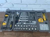 Full open plastic toolbox showing all tools inside including wrenches, screwdrivers, sockets, tape measure, cutters.