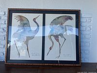 Full view of the framed artwork showing two watercolor crane paintings side by side, matted and framed under glass.