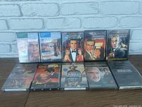 10 movie DVDs displayed in 2 rows of 5, showing front covers and cases against a white brick background.